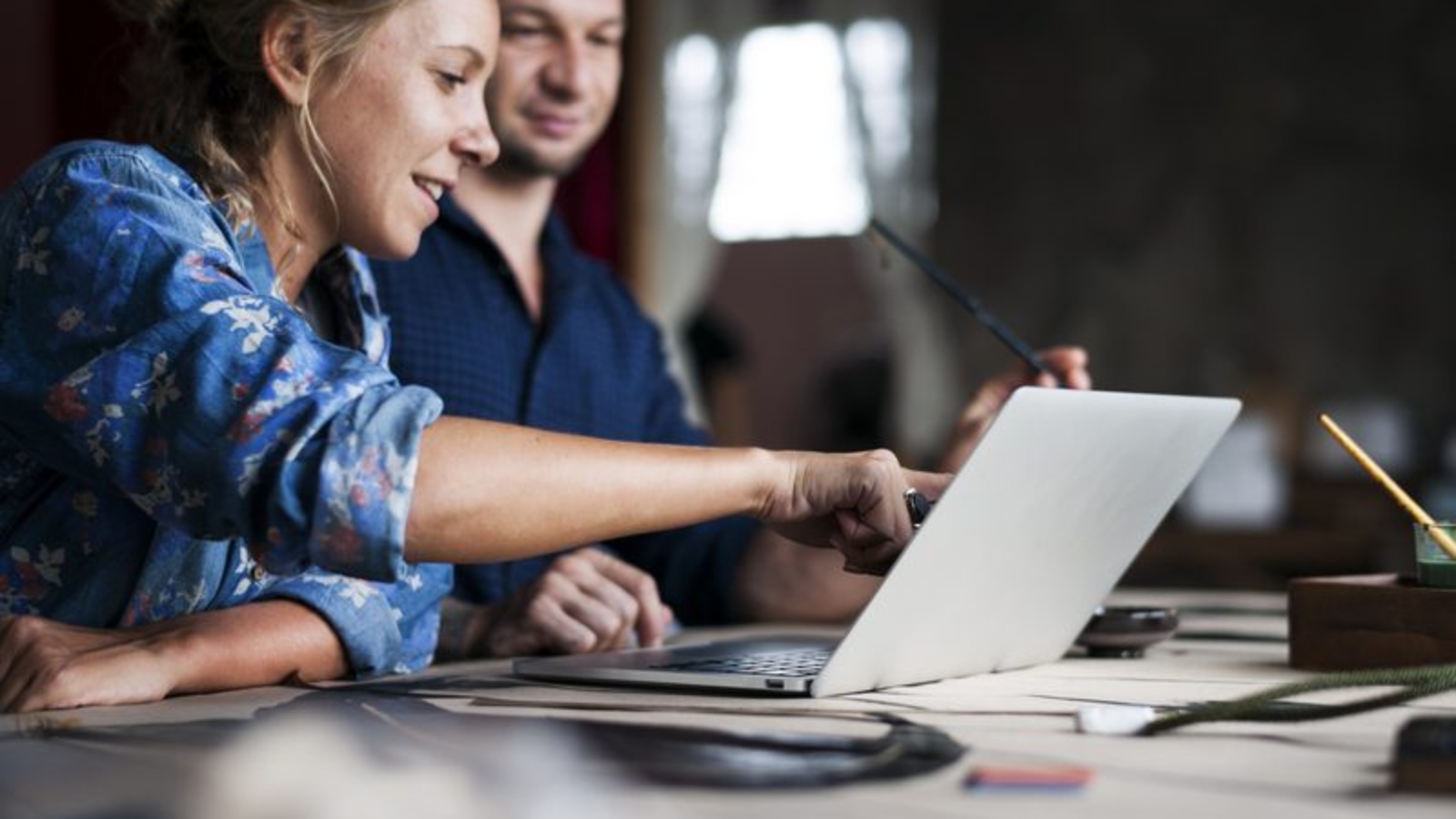 Caucasian woman poiting on computer laptop showing colleague