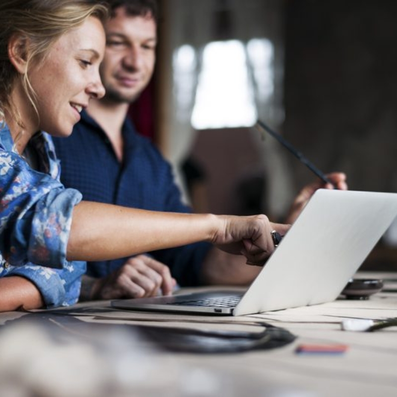 Caucasian woman poiting on computer laptop showing colleague