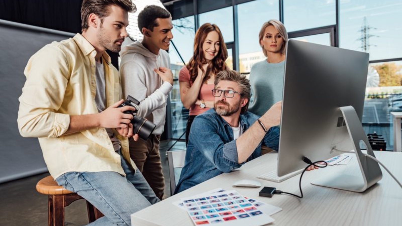 selective focus of creative director looking at happy assistants in photo studio